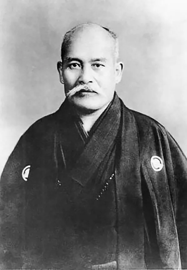 Formal portrait photograph of Ueshiba Morihei in 1939, seated in a dark kimono with a short beard.
