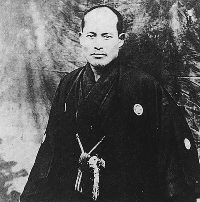 Photograph of a young Ueshiba Morihei around 1918, stocky and moustached, in Japanese dress.