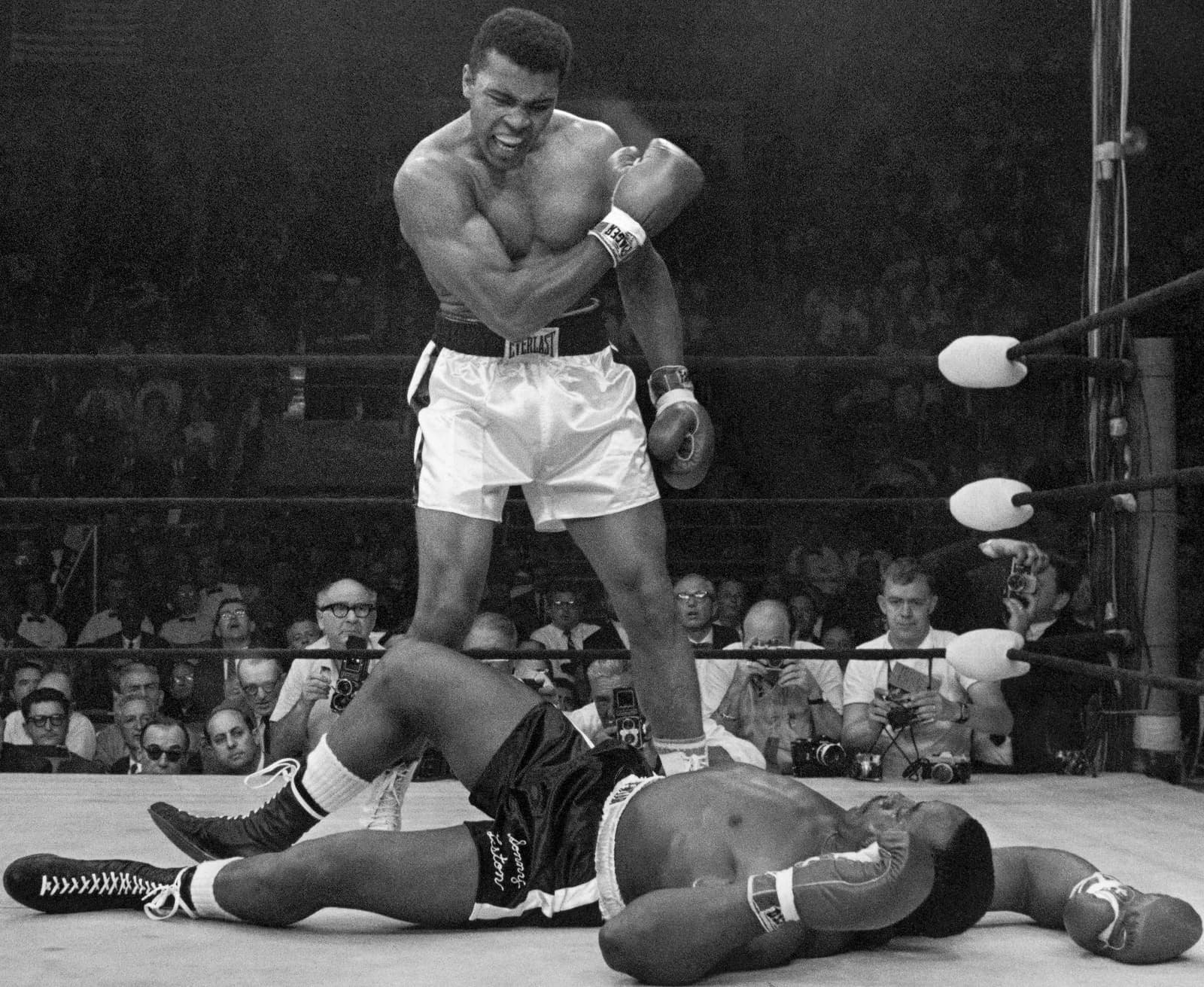 Muhammad Ali stands over a fallen Sonny Liston, right arm cocked, shouting at him to get up, Lewiston, Maine, 1965.