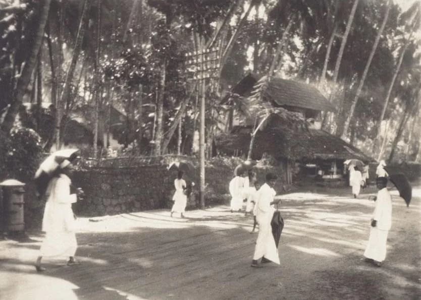 Early 20th-century photograph of a street in Kozhikode (Calicut), Kerala, with low buildings and people.