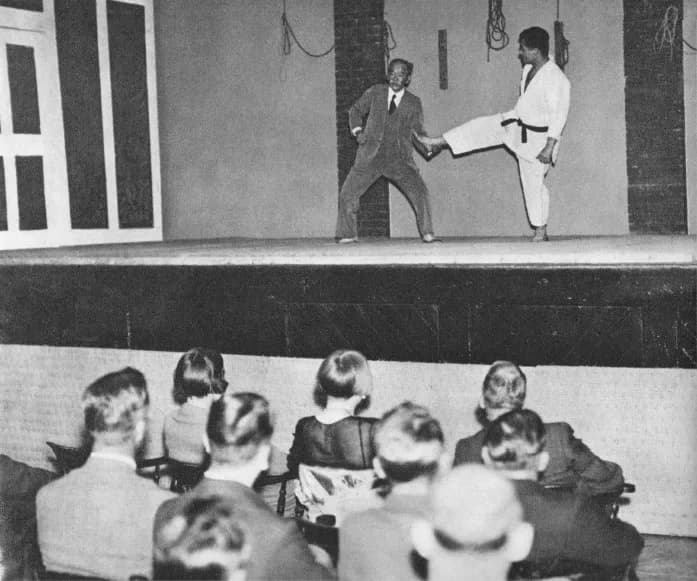 Jigorō Kanō, in his seventies and wearing a judogi, demonstrates a technique on Sumiyuki Kotani in 1933.