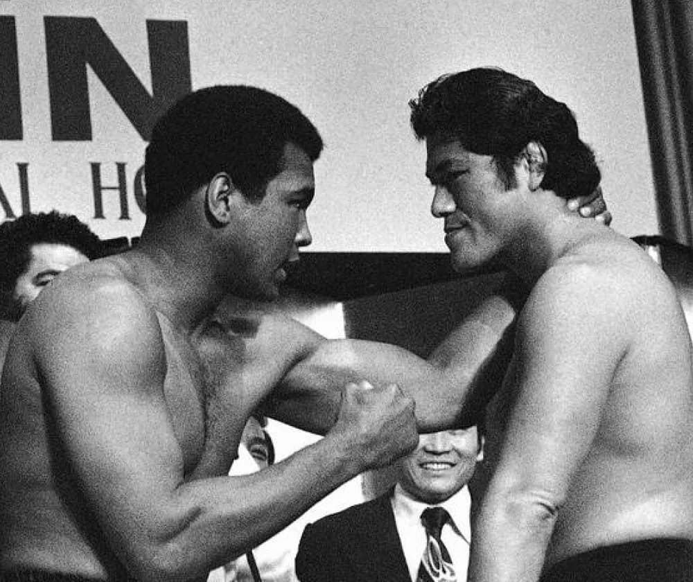 Muhammad Ali and Antonio Inoki face each other at the weigh-in for their 1976 fight, surrounded by officials.