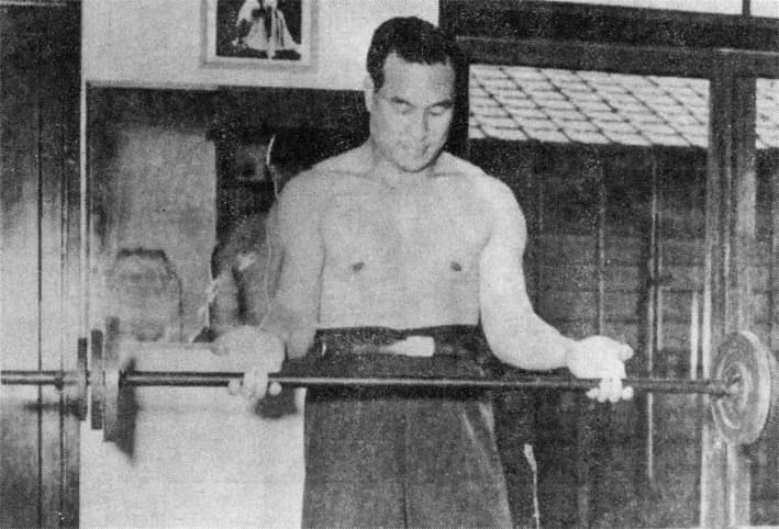 Mas Oyama training outdoors in 1951, striking in a low stance.