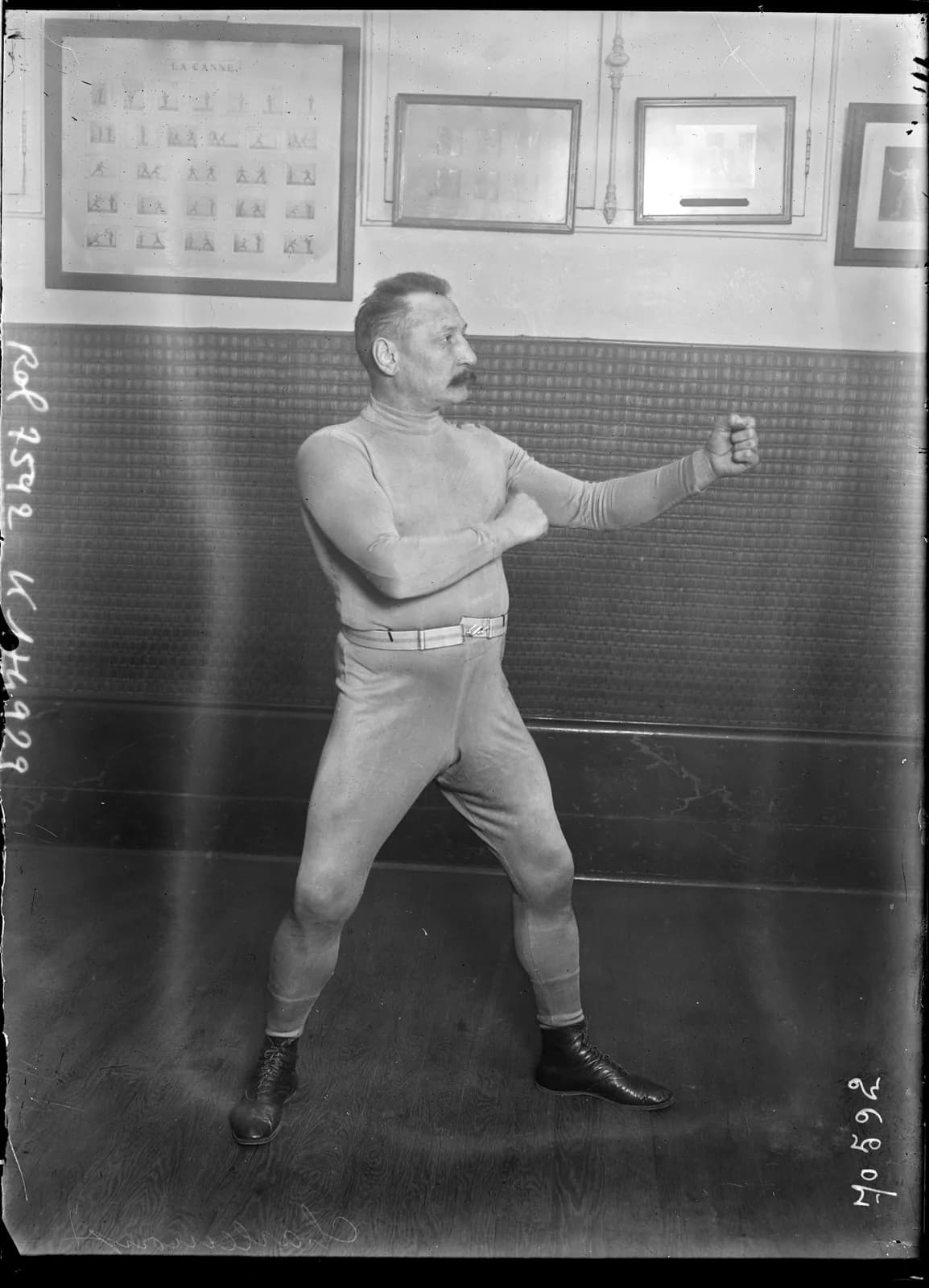 Charles Charlemont, a boxe française teacher, posing alone in a fighting stance in a gymnasium in 1921.